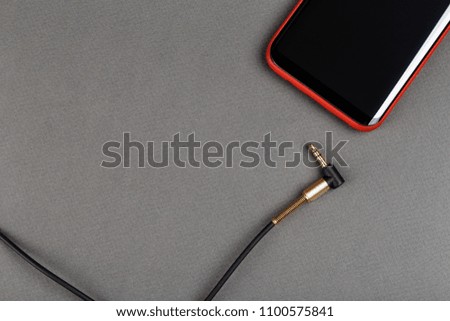 audio cable mini jack and mobile phone on a gray background
