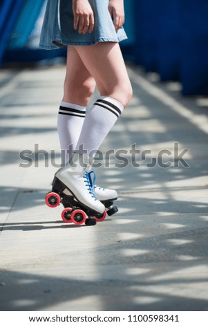 cropped shot of girl in denim skirt and vintage roller skates on street