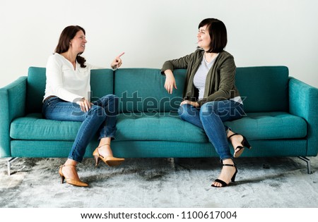 Women talking together on the couch Royalty-Free Stock Photo #1100617004