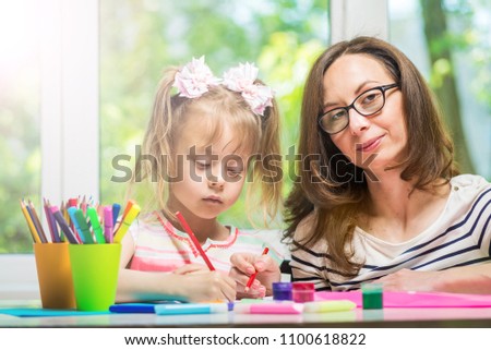 Happy family. Mother and daughter together paint. Woman helps the child girl.