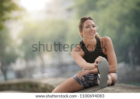 Athletic woman stretching out after running Royalty-Free Stock Photo #1100694083