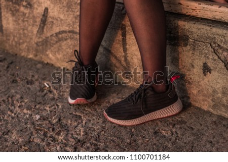 informal girl feet in black tights and sneakers concept on concrete floor with empty space for copy or text