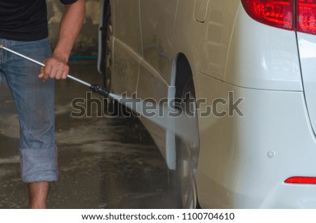 Men run car wash with high pressure water.