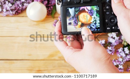 takes a photo with still life with lilac flowers and cream cosmetic by photo camera 