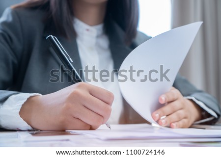 Asian Business woman Manager checking and signing applicant filling documents reports papers company application form or registering claim on desk office. Document Report and business busy Concept