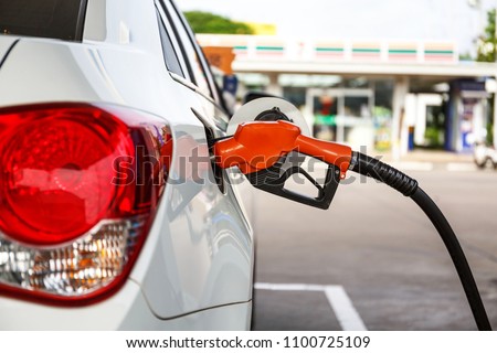 transportation and ownership concept - man pumping gasoline fuel in car at gas station Royalty-Free Stock Photo #1100725109