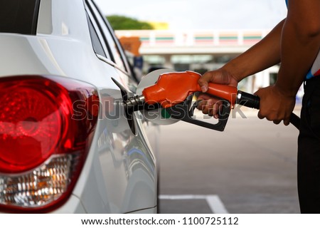 transportation and ownership concept - man pumping gasoline fuel in car at gas station Royalty-Free Stock Photo #1100725112