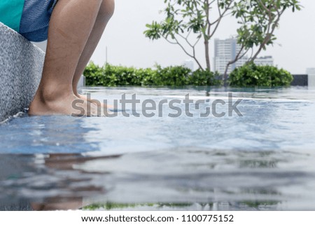 Close-up of a kid foot Sitting at the edge of the pool and enjoy.