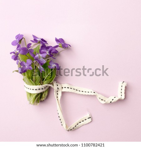 violet flowers in bouquet on pink background, flat lay. Spring, summer romantic minimal concept