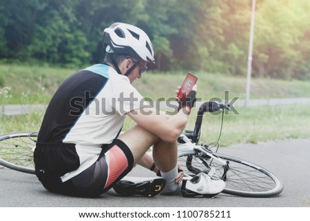 Injured biker holding his smartphone calling rescue team with simple user-friendly smart phone application 