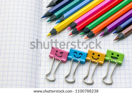 
Color pencils and colored paper clips on a notebook sheet