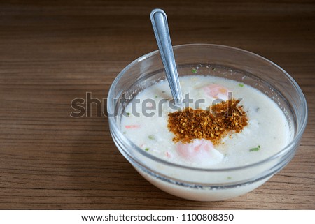 Rice porridge with egg in bowl on wood table,Cayenne pepper flavored.