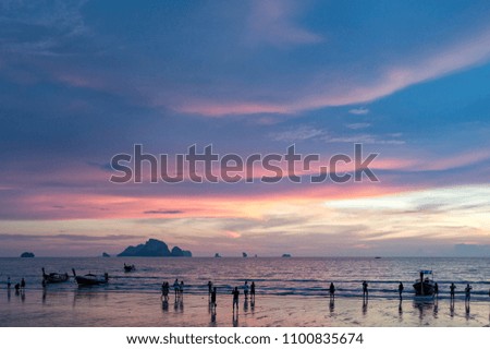 Tourists taking a picture of beautiful sunset on the Ao Nang beach in Krabi province, Thailand
