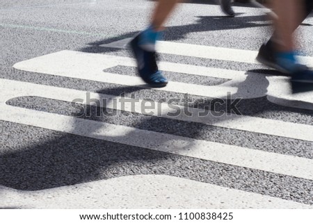 closeup side view of marathon runners feet and legs with motion blur running in the light of the morning on city tarmac road
