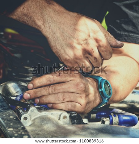 Man at work in a garage. Auto mechanic worker in car repair service. Detail image of mechanic hands with a tool. Auto repair concept. Close up. Beautiful vintage. Nice background for your text Matte. 