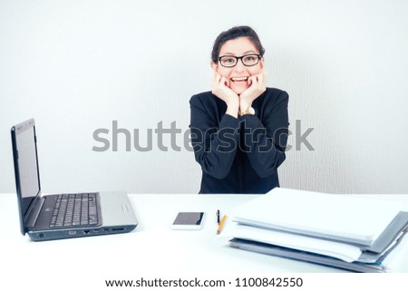 beautiful happy business woman (lady) brunette in stylish suit is happy ecstatic sitting at the desk with a laptop and a bunch of folders in the office