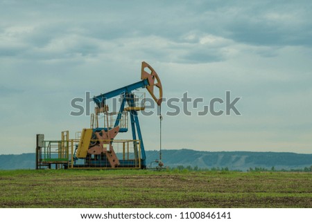 extraction oil drilling pump, fuel production. black gold. against the background of the sky of the mountains. barrel oil