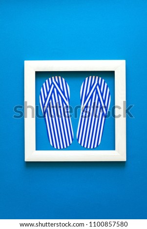 Minimalism. Masterpiece in wooden frame. Flip-flops. Top view. Flat lay. Summer travel concept. Origami