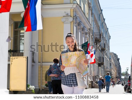 girl walks down the street among the facades of buildings and looks at the paper map, the girl in St. Petersburg