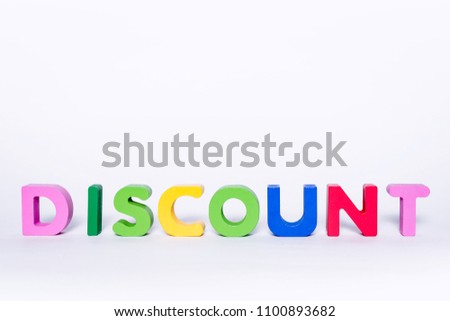 Word DISCOUNT on an isolated white background. DISCOUNT message made up of wooden and colorful letters with scattered letters. Discount concept in the store.