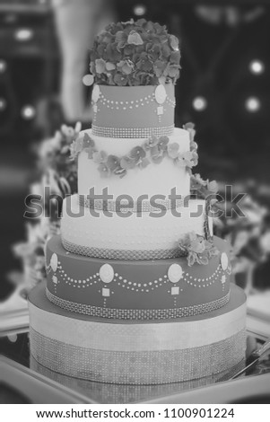 One big beautiful tasty many-tier decorated wedding cake white and blue colours with flower garlad and hydrangea bouquet on top, vertical picture