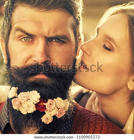 Passionate couple kissing, boy and girl. beautiful couple of woman kissing man with long black beard with many little white red and pink flowers sunny day outdoor on natural background, square picture