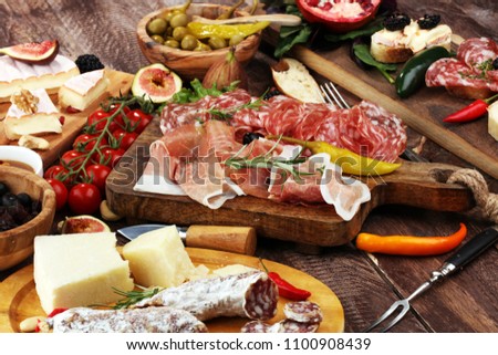 Italian antipasti wine snacks set. Cheese variety, Mediterranean olives, pickles, Prosciutto di Parma, pepper and salami Royalty-Free Stock Photo #1100908439