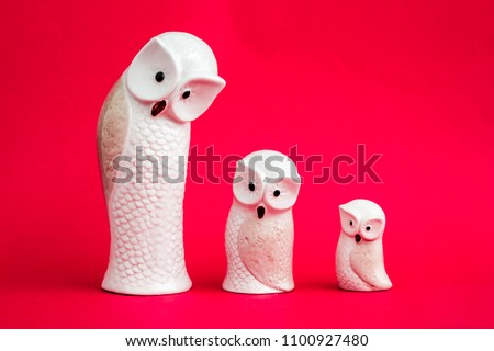Statuettes of white owls on pink background