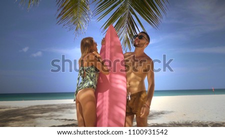 Young happy couple in swimwear having fun, enjoying sunny summer day on their beach tropical holiday