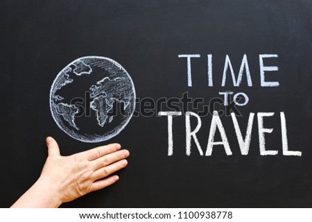 Chalk inscription "Time to travel" on a blackboard. Female hands hold the globe against a chalkboard background.