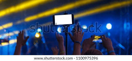 Young people shoot photos or video of a concert on smartphones.