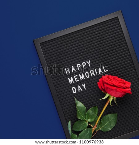 Black letterboard with white plastic letters with quote Happy Memorial Day, and rose on navy blue background. Square crop.