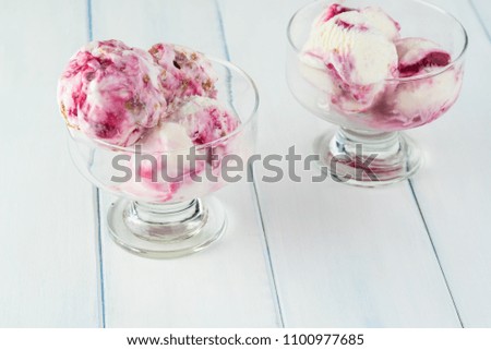 Bowls with scoops of raspberry cheesecake gelato ice cream on a wooden background.