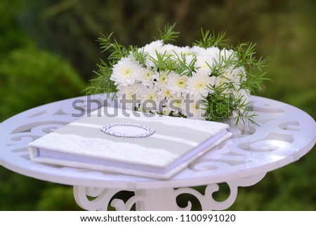 wedding elements, guest book and gift box of flowers on white carved wooden table