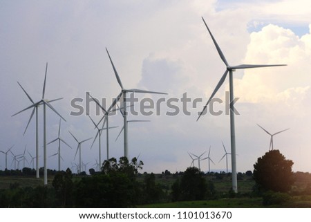 There are wind turbines with grass field background in the evening .