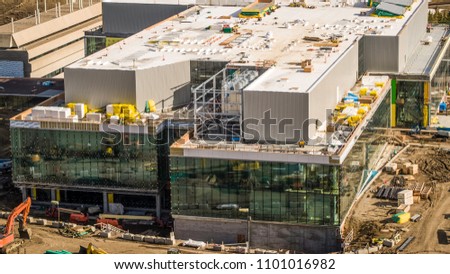 Busy Construction site commercial building, large glass walls, warm tones