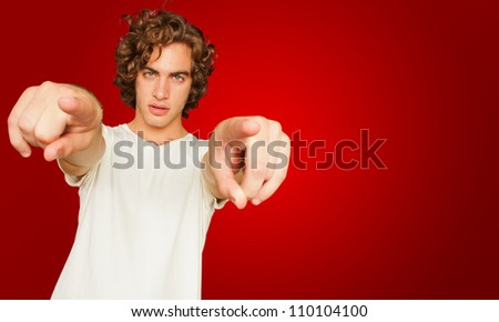 Portrait Of Young Man Pointing With Hand On Red Background