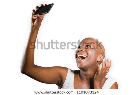 young beautiful and happy black afro American woman smiling excited taking selfie picture portrait with mobile phone or recording self portrait video posing cheerful having fun on isolated background