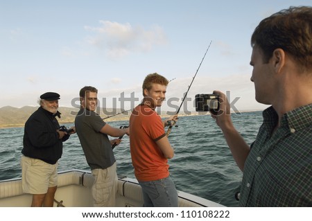 Man taking snapshot of friends fishing on yacht