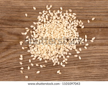Heap of white sesame seeds on wooden background 