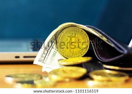bitcoins whit money in black leather wallet near computer.