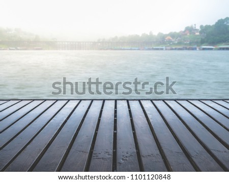 Wetting dark planks floor of raft floating on the wide river in the rainy day