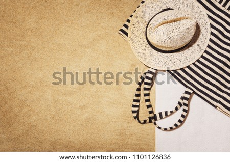 Top view of sandy beach with towel frame and summer accessories. Background with copy space and visible sand texture. Border composition made of towel