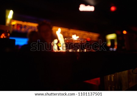 The bartender creates a fiery show behind the bar. photo in the dark.