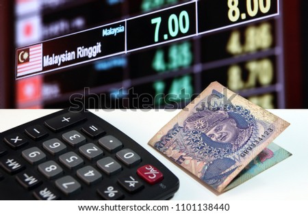 One ringgit banknote of Malaysia and calculator on the white floor with digital board of currency exchange money background, the concept of finance.