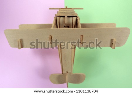 The wooden plane on fashionable pastel colored paper flat lay top view, geometric background texture, pink, green color.