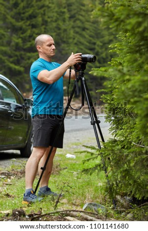 Photographer with camera on tripod shooting a macro scene
