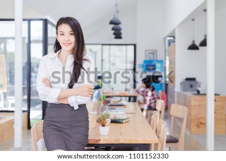 Portrait of Modern asian business woman standing cross one's arm in the coworking with copy space.