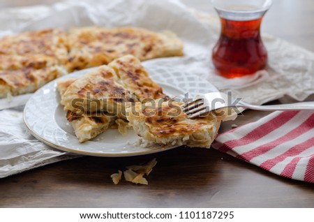 Sliced cheese pastry on the table, next to the turkish tea.(shallow depth of field)