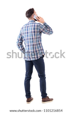 Back view of smart casual young man talking on the cell phone and looking up. Full body isolated on white background.